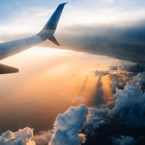 plane flying through sunset for travel insurance